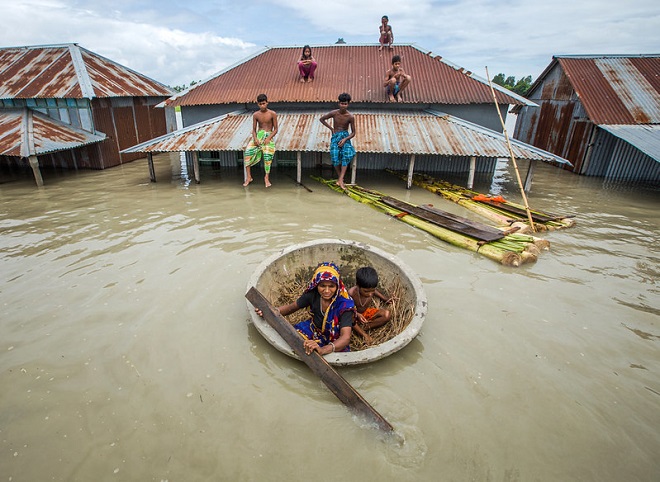 Bildet viser mennesker i Bangladesh som manøvrerer seg frem etter en oversvømmelse.